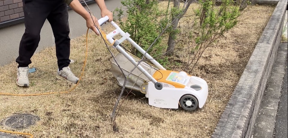 電動芝刈り機で芝生を刈っている様子